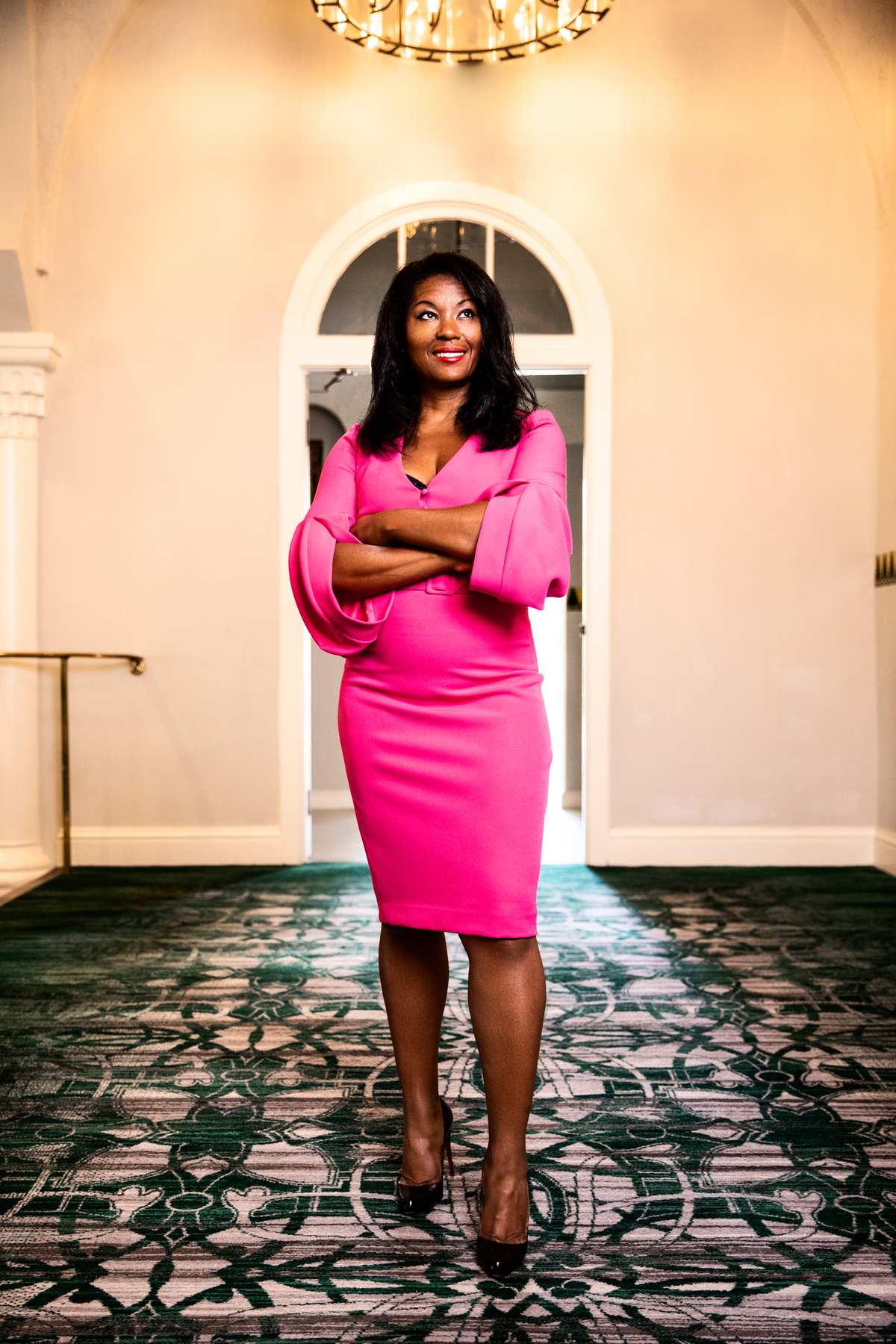 Kimberly G. Jackson in a pink dress standing in an elegant hallway