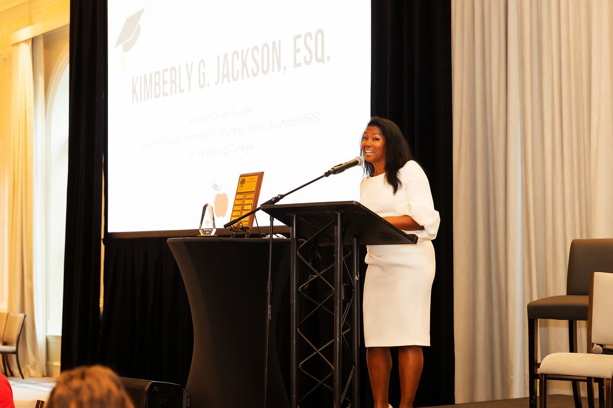 Kimberly G. Jackson on stage at Academy Prep with her name displayed on screen